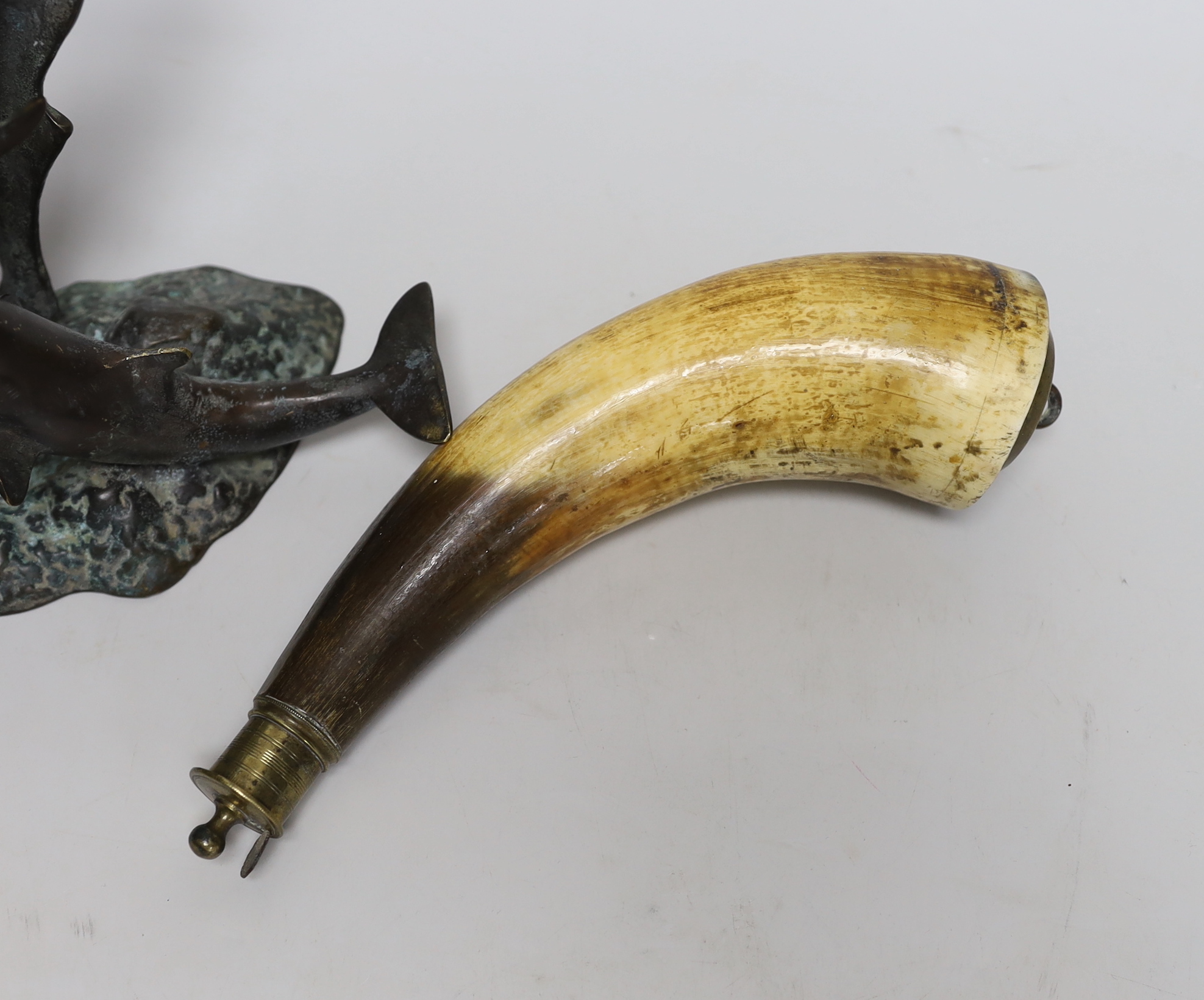 A 19th century powder horn and a cast brass dolphin group, powder horn 23cm long